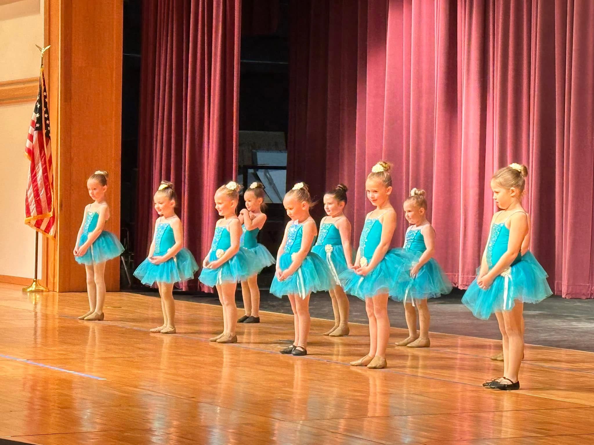 A line of young Chickasha School of Dance students in teal tutus performing together on stage
